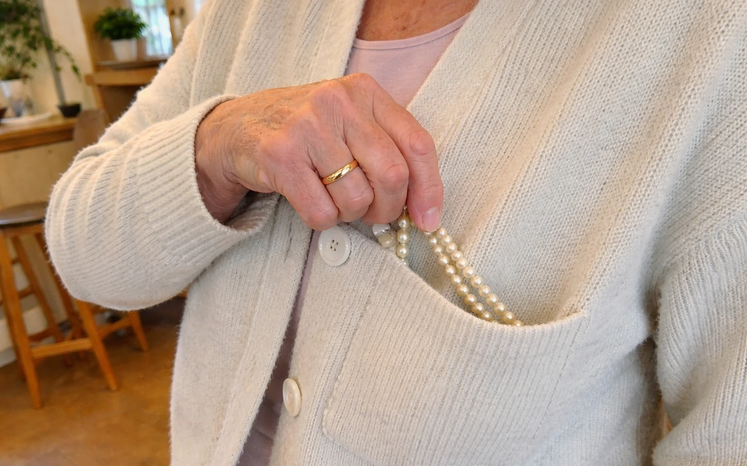 Woman takes a pearl necklace out of her pocket | AI-generated image